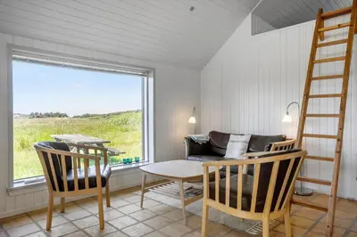 a living room with a table and chairs and a ladder at 957-Thisted-Hvidbakken-33-Lille-hus in Torsted