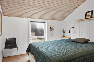 a bedroom with a bed and a chair and a window at 904-Thisted-P-Bolesens-Vej-15 in Torsted