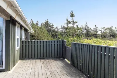 a black fence next to a house with a wooden deck at 1052-Thisted-Bavnbak-50 in Torsted