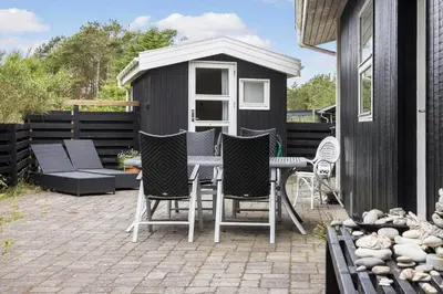 a patio with chairs and a table and a shed at 458-Thisted-Sandtornvej-18 in Thisted
