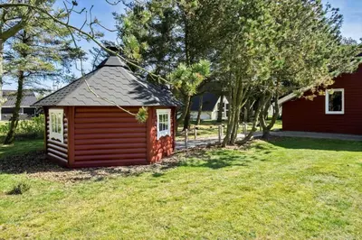 a small red building in the grass next to a house at 854-Thisted-Molgaardsvej-3 in Thisted