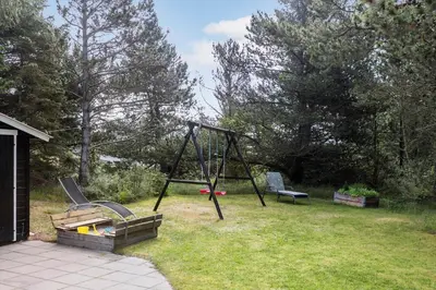a playground with a swing and two chairs in a yard at 834-Thisted-Revlingvej-9 in Thisted