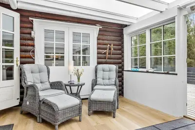 a porch with chairs and a table and windows at 997-Thisted-Lyngstien-15-B in Torsted