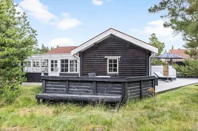 a log cabin with a deck in front of a house at 997-Thisted-Lyngstien-15-B in Torsted