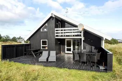 a black house with a deck in a field at 376-Thisted-Fiskervej-55 in Thisted