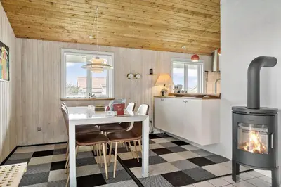 a kitchen with a fireplace and a table and a stove at 928-Thisted-Kobbelsti-15 in Torsted