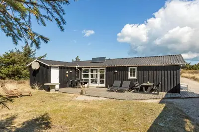 a black cottage with a deck and patio at 744-Thisted-Orredvej-26 in Thisted