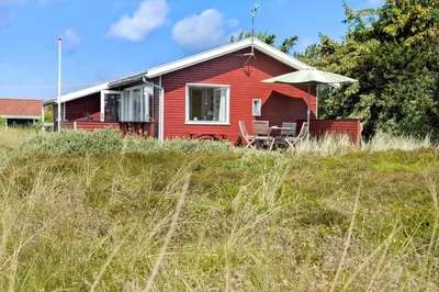 a red house with a table and an umbrella at 240-Thisted-Hummervej-10 in Thisted