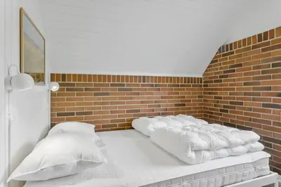 a bed with white sheets and a brick wall at 479-Thisted-Kristinesvej-36 in Thisted