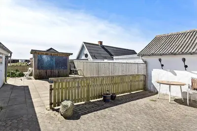 a backyard with a wooden fence and a table at 758-Vestervig-Vesterhavsvej-28 in Vestervig