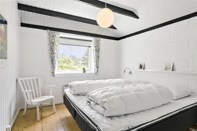a white bedroom with a large bed and a chair at 344-Thisted-Flyndervej-20 in Thisted