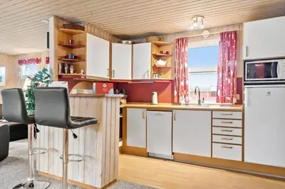 a kitchen with white cabinets and a black chair at 860-Thisted-Gronnevej-6 in Thisted