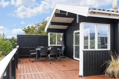 a black house with a deck with a table and chairs at 567-Thisted-Fiskervej-67 in Thisted
