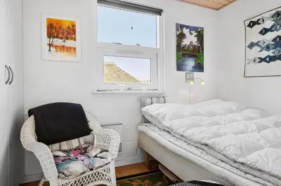 a bedroom with a white bed and a wicker chair at 1332-Thisted-Flyndervej-22 in Thisted