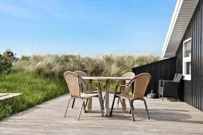 a patio with a table and chairs on a deck at 1062-Thisted-Mombak-45 in Torsted