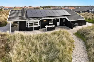 a black house with solar panels on the roof at 1062-Thisted-Mombak-45 in Torsted