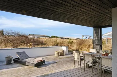 a patio with a table and chairs on a deck at 1064-Thisted-Klitstien-25 in Torsted