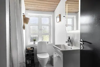 a bathroom with a toilet and a sink and a window at 1350-Thisted-Blabaervej-22 in Thisted