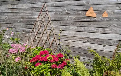 a garden with flowers in front of a wooden fence at Lovely Home In Thyholm With Wifi in Thyholm