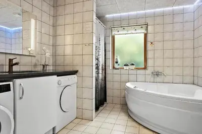 a bathroom with a tub and a sink and a washing machine at 1351-Thisted-Mose-Bollevej-13 in Thisted