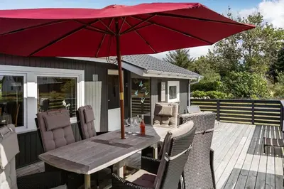a wooden table with a red umbrella on a deck at 1353-Snedsted-Ebenezervej-24 in Snedsted