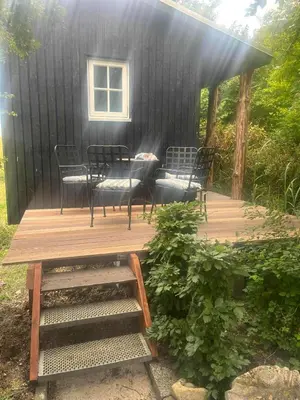 a black house with chairs and a table on a deck at Lykkeholms Bella Vista in Spottrup