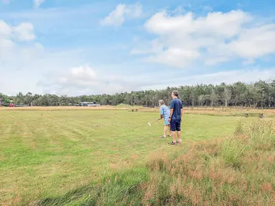 two people standing in a field with a baseball bat at 5 person holiday park home in Pandrup in Pandrup