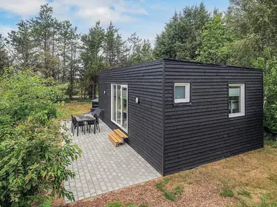 a black tiny house with a patio and a table at 5 person holiday park home in Pandrup in Pandrup