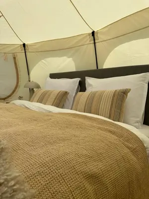 a bedroom with a large bed with white pillows at Agger Glamping - Havtornen in Vestervig