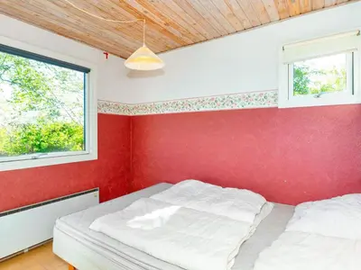 a bedroom with a red wall and a bed at 5 person holiday home in Roslev-By Traum in Roslev