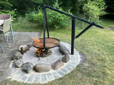 a fire pit with a grill in a yard at Family Cabin By The Calm Waters Of Limfjord in Højslev