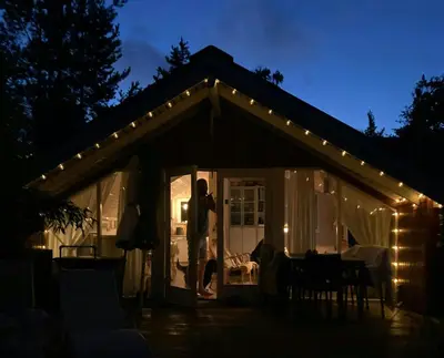 a man standing in the doorway of a house with lights at Family Cabin By The Calm Waters Of Limfjord in Højslev