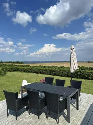 a table with chairs and an umbrella on a deck at Summer House With Wilderness Bath And Water Views in Vinderup