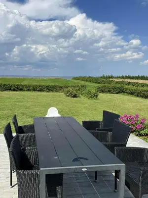 a black table and chairs with a view of a field at Summer House With Wilderness Bath And Water Views in Vinderup