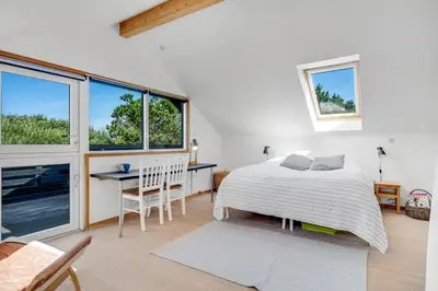 a bedroom with a bed and a table and chairs at Lovely Holiday Home With Wood-Burning Stove, Close To The North Sea In Klitmøller in Thisted