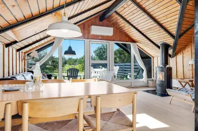 a living room with a wooden ceiling and a table and chairs at Lovely Holiday Home With Wood-Burning Stove, Close To The North Sea In Klitmøller in Thisted