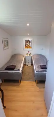 two beds in a small room with wooden floors at Blokhus - tæt på by og strand in Blokhus