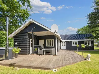 a small black house with a wooden deck at 6 person holiday home in Thyholm-By Traum in Thyholm