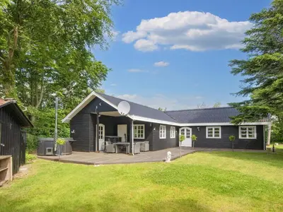 a black house with a patio and a yard at 6 person holiday home in Thyholm-By Traum in Thyholm