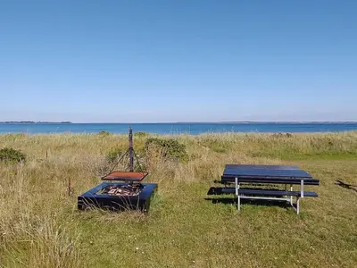 two picnic tables and a grill in a field at 6 person holiday home in Thyholm-By Traum in Thyholm
