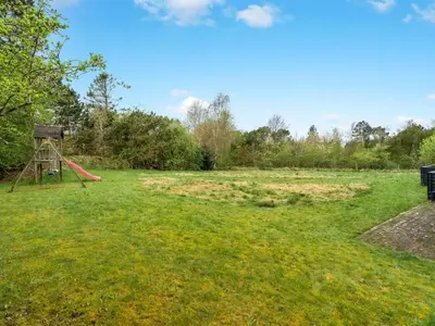 a playground in a field with a red slide at Holiday Home Ginne - 1km to the fjord by Interhome in Løgstør