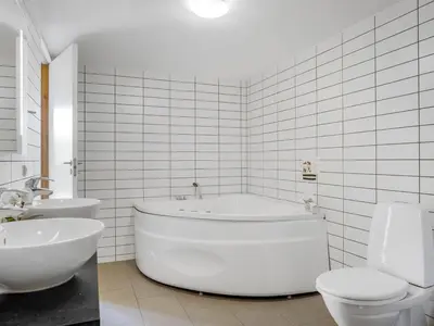 a white bathroom with a tub and two toilets at Holiday Home Ginne - 1km to the fjord by Interhome in Løgstør