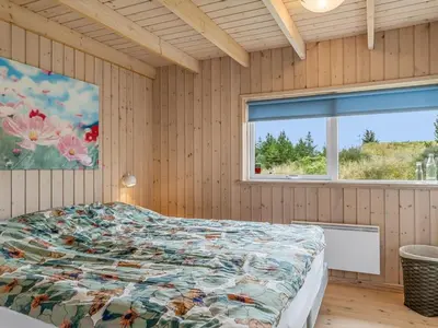 a bedroom with a bed with a colorful comforter and a window at Holiday Home Selvi - 2-2km from the sea by Interhome in Blokhus