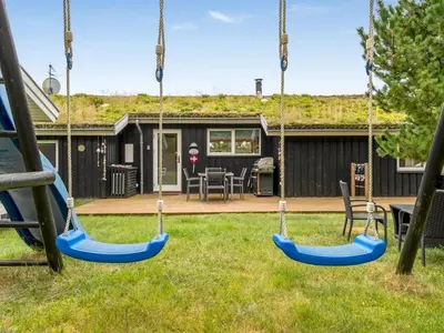 two swings in a yard with a house at Holiday Home Selvi - 2-2km from the sea by Interhome in Blokhus