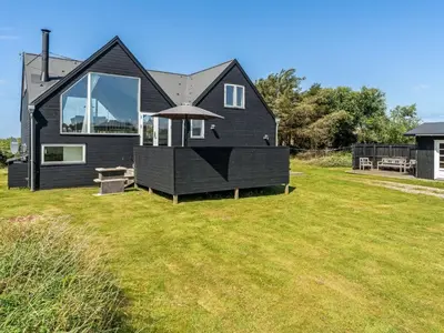 a black house on a yard with a grass field at Holiday Home Tekla - 180m from the sea by Interhome in Blokhus