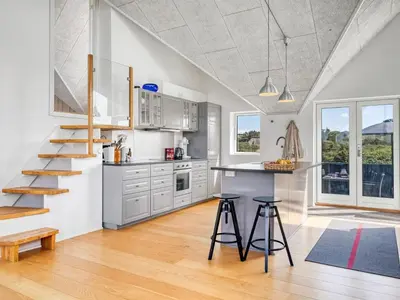 a kitchen with a staircase and a counter with stools at Holiday Home Tekla - 180m from the sea by Interhome in Blokhus