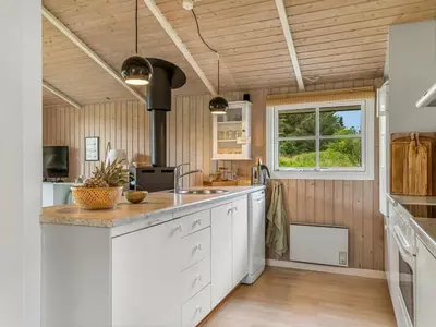 a kitchen with white cabinets and wooden walls at Holiday Home Nahuel - 1km from the sea by Interhome in Blokhus