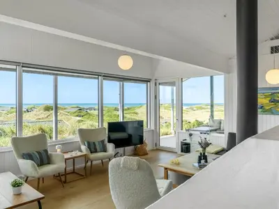 a bedroom with a bed and chairs and a television at Holiday Home Jannus - 600m from the sea by Interhome in Saltum