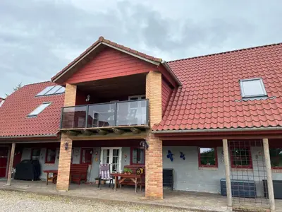 a house with a red roof with a deck at Stor lejlighed i landlige omgivelser in Bækmarksbro