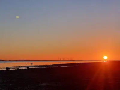 a sunset on a beach with the sun setting at 6 person holiday home in Brovst-By Traum in Brovst